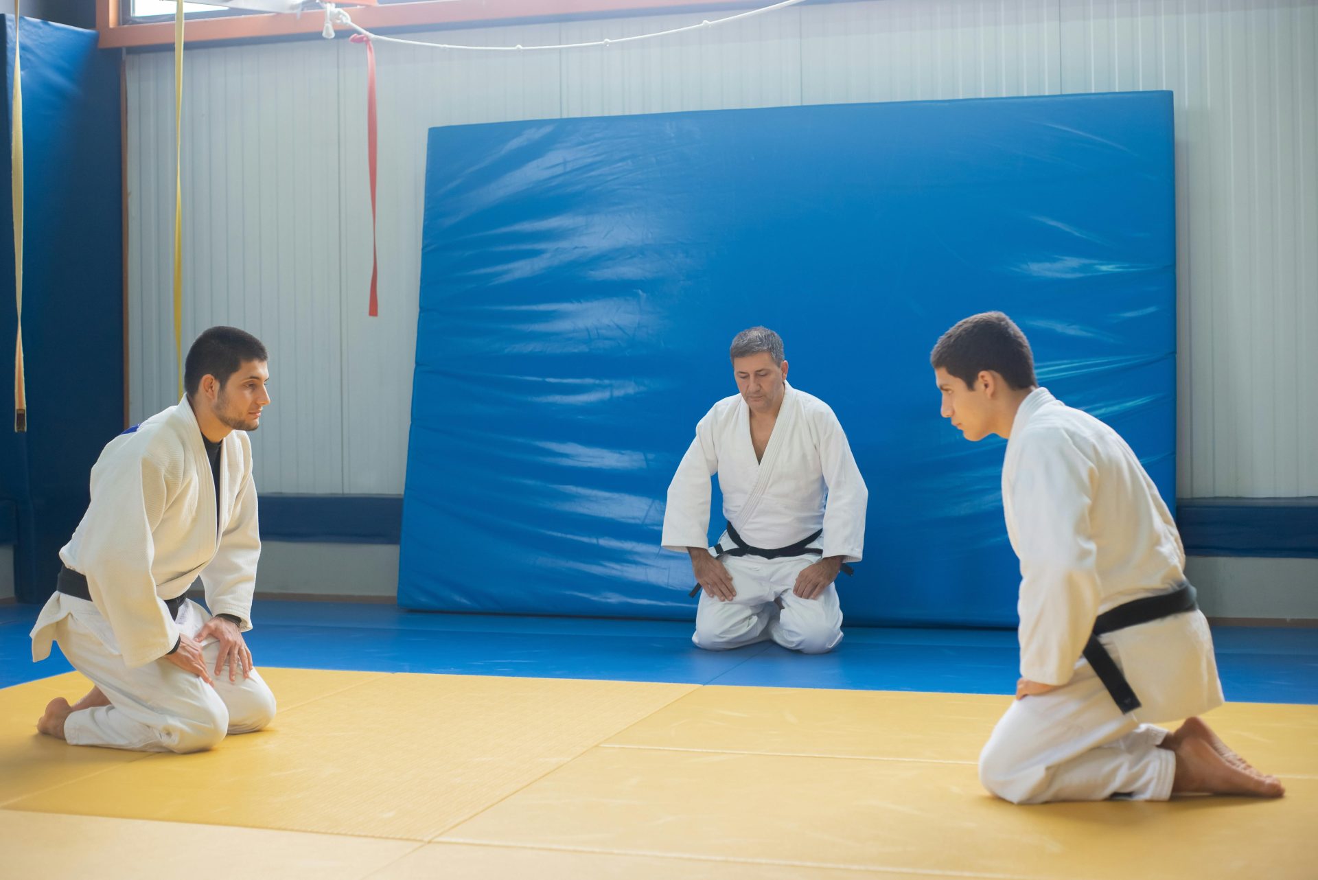 Martial artists in a judo dojo practicing under instruction, showcasing sportsmanship.