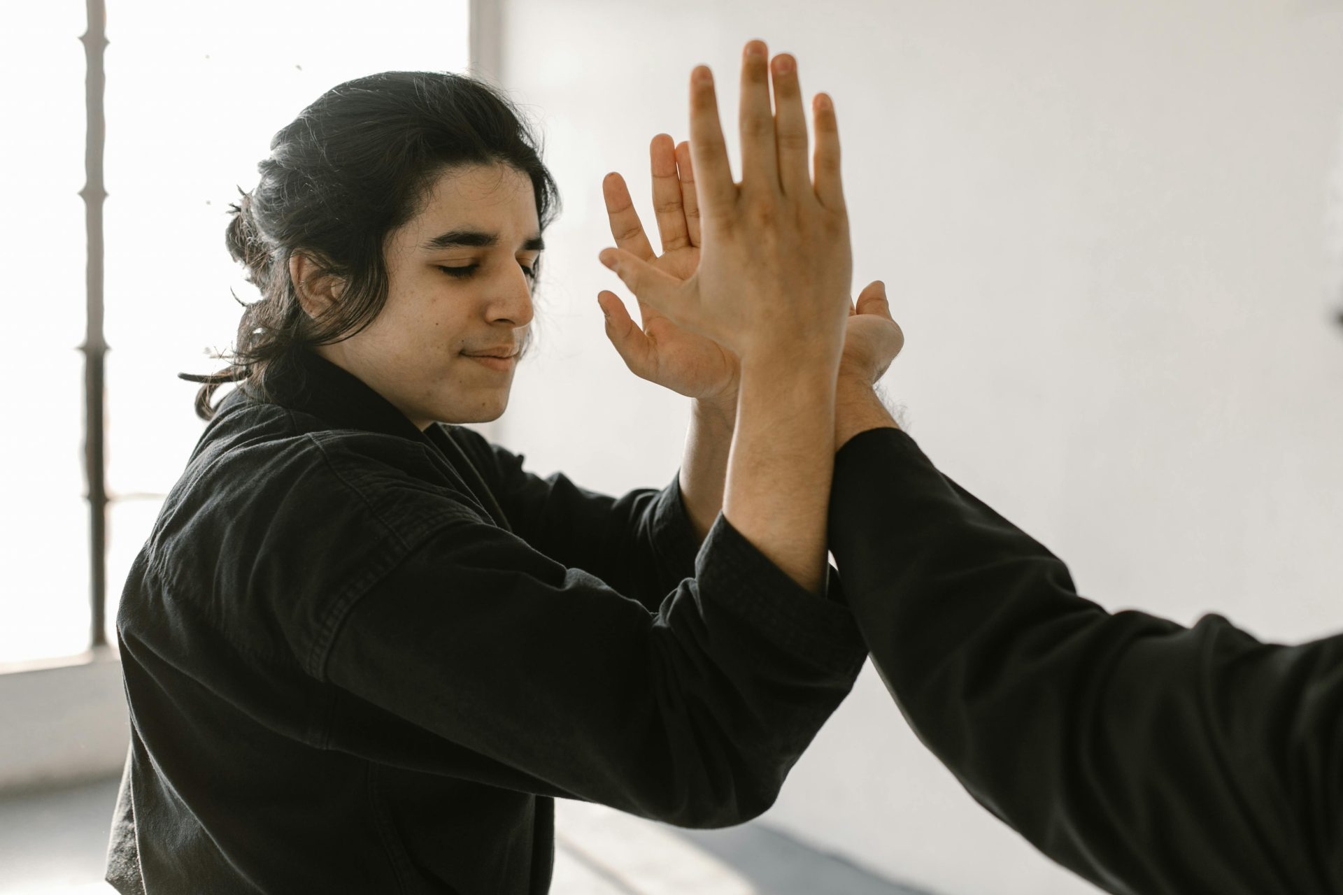 Two martial artists practicing techniques indoors with focus and precision.