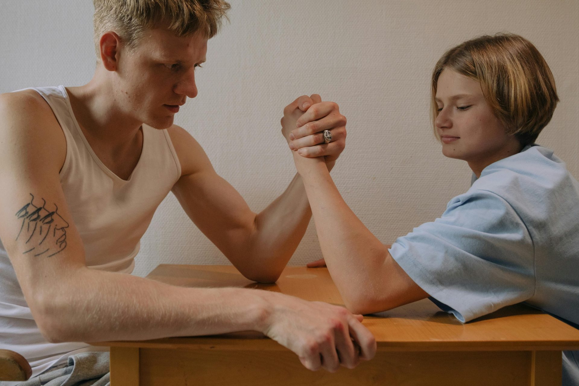 Two siblings engage in a focused arm wrestling match at home.