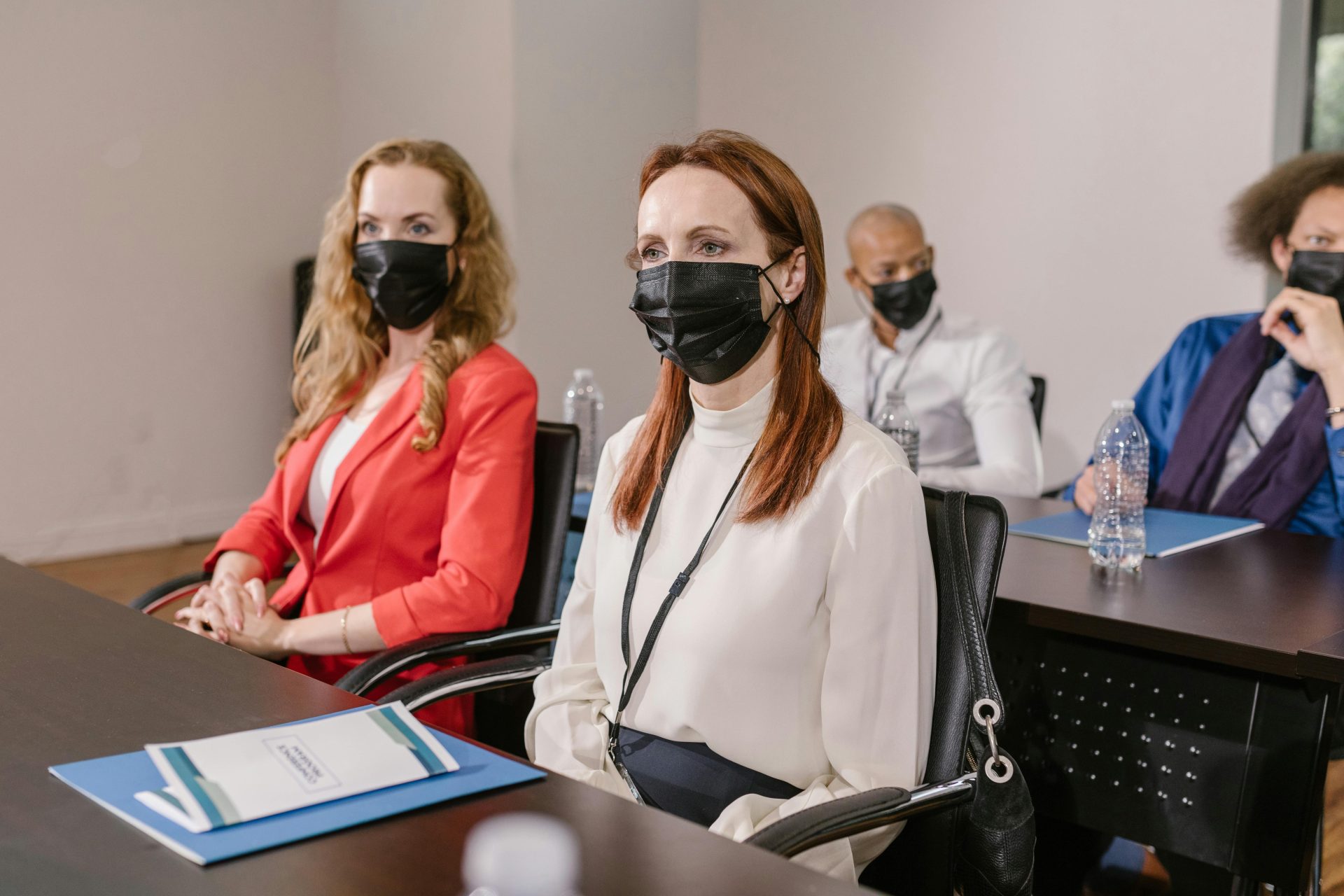 Diverse group of professionals in masks attending a business conference indoors.